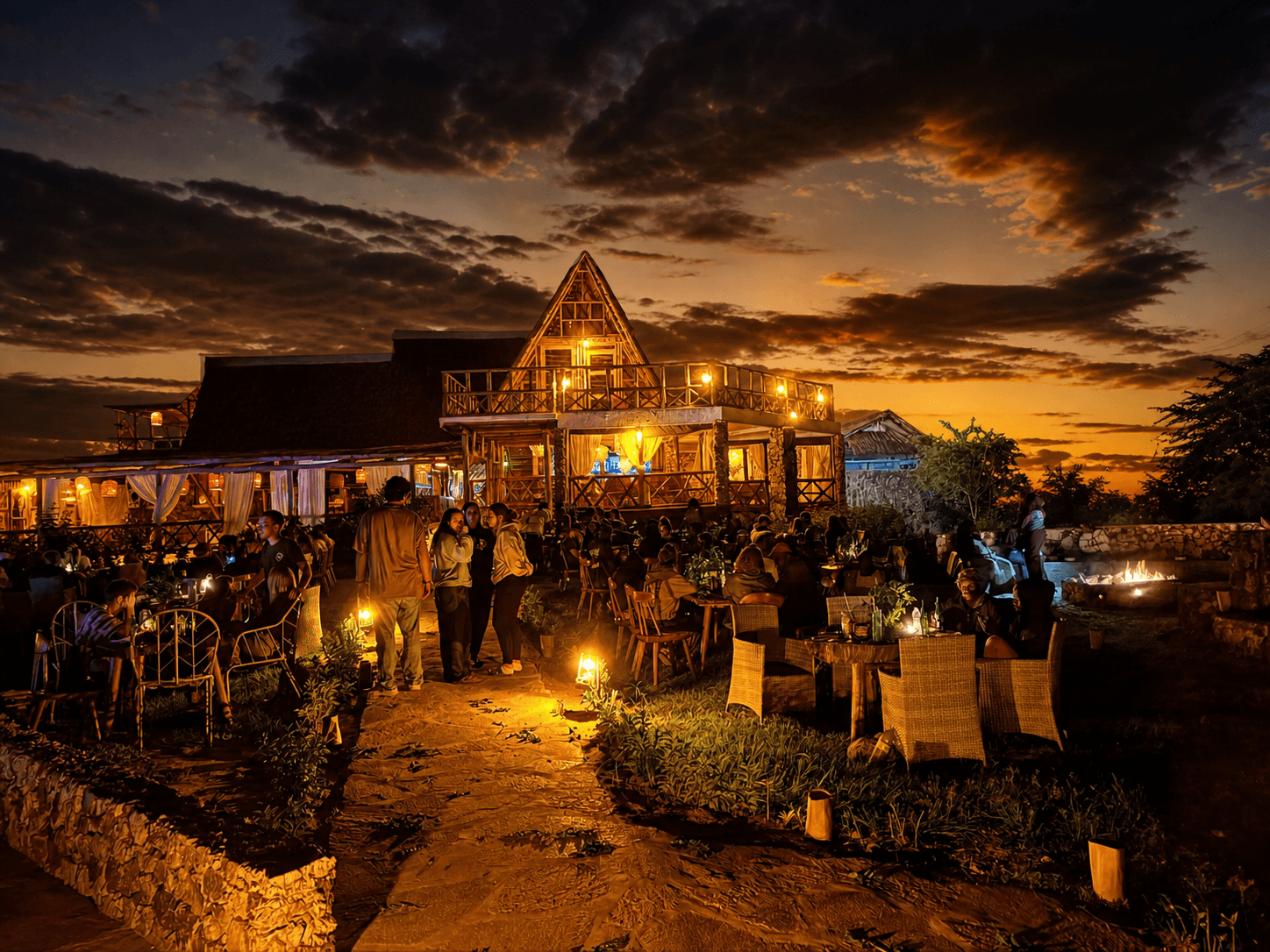 The Elephant Oasis lodge at night with guests gathered at the fire pit, Murchison Falls Uganda