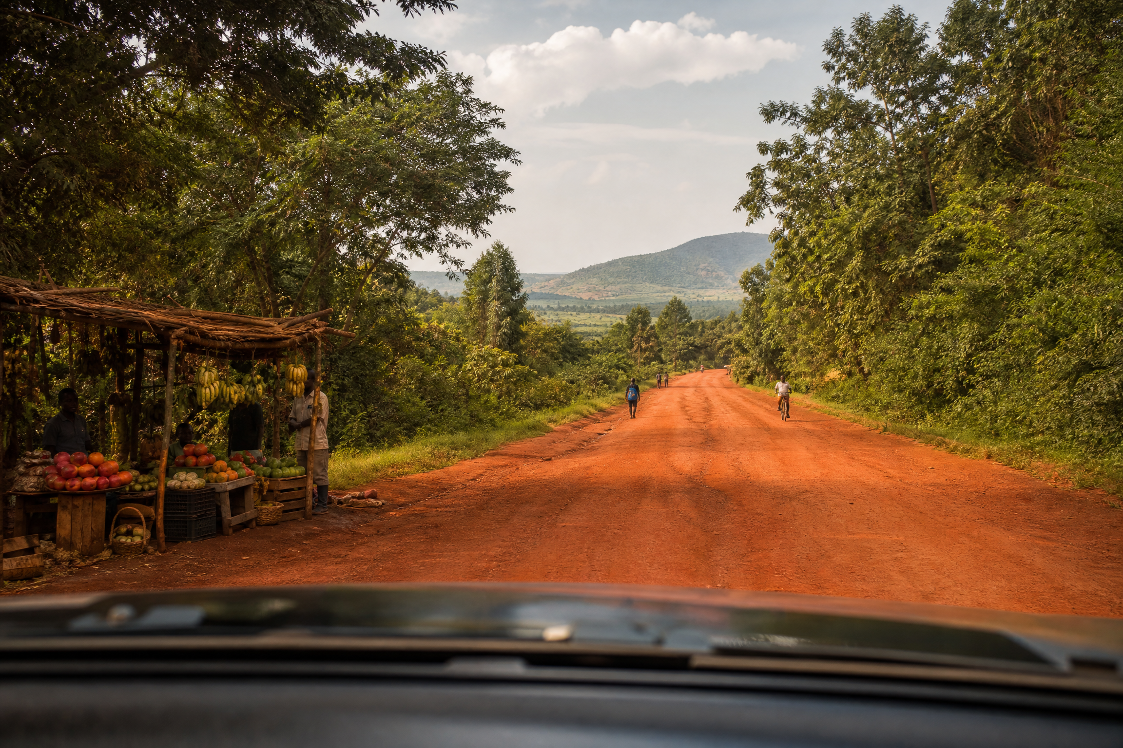 Red laterite road through lush green Ugandan countryside on the drive north from Entebbe to Murchison Falls National Park