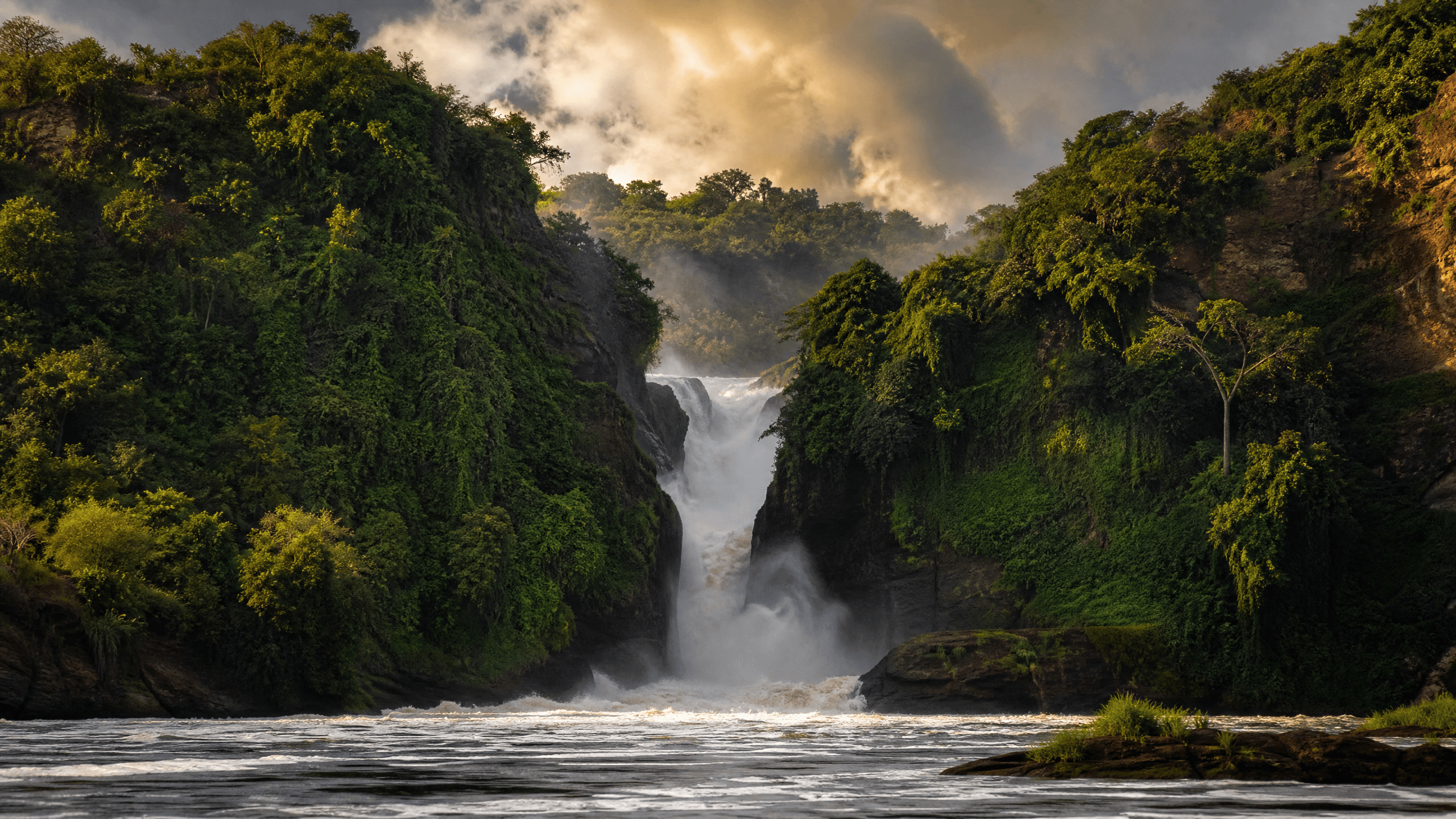 Murchison Falls — the Nile River forced through a narrow gorge and dropping into the pool below, surrounded by lush green vegetation