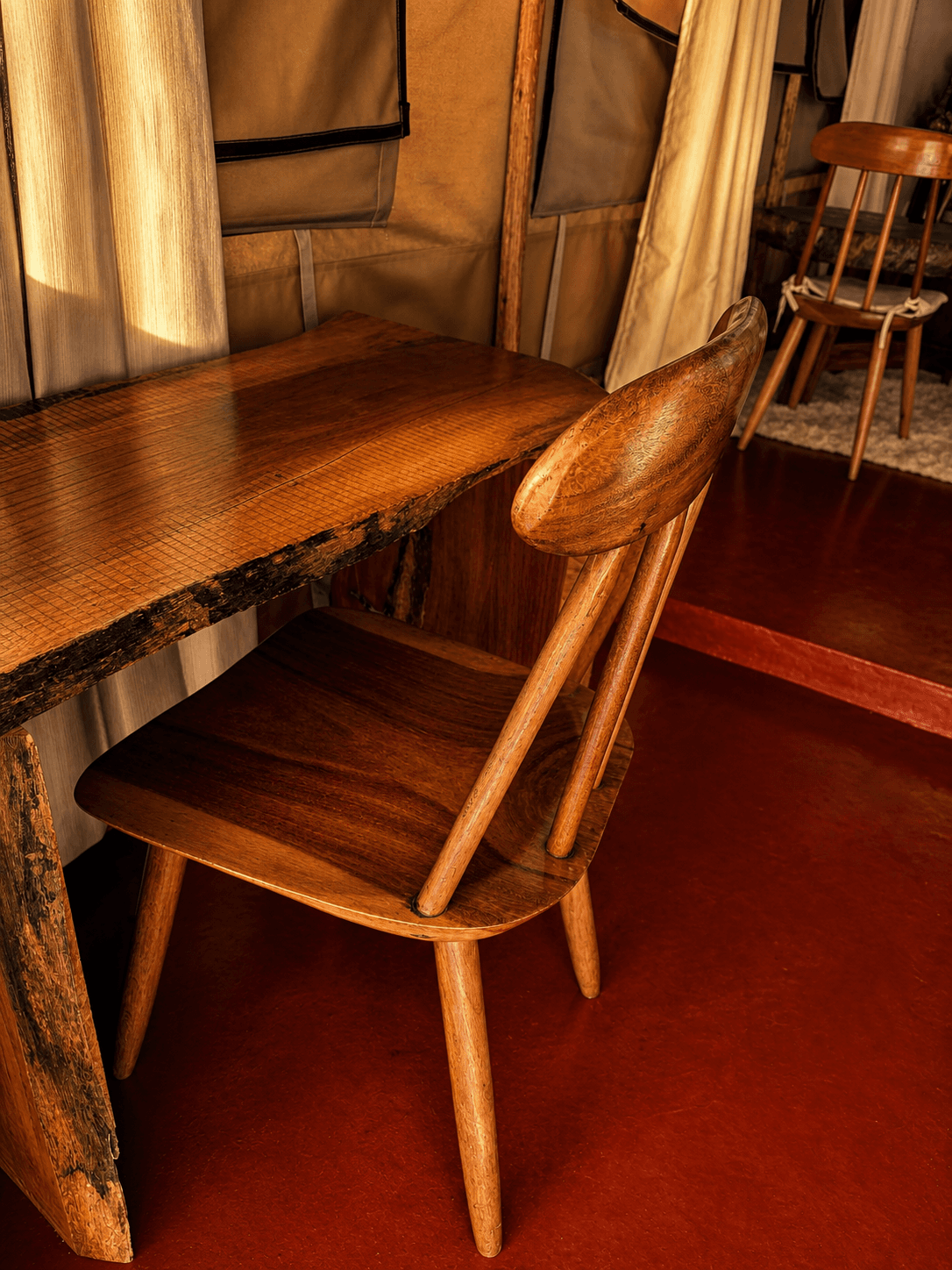 Luxury Safari Tent work desk at The Elephant Oasis — live-edge wooden desk with natural bark edges, handmade wooden chair, canvas tent walls, warm afternoon light, Murchison Falls Uganda