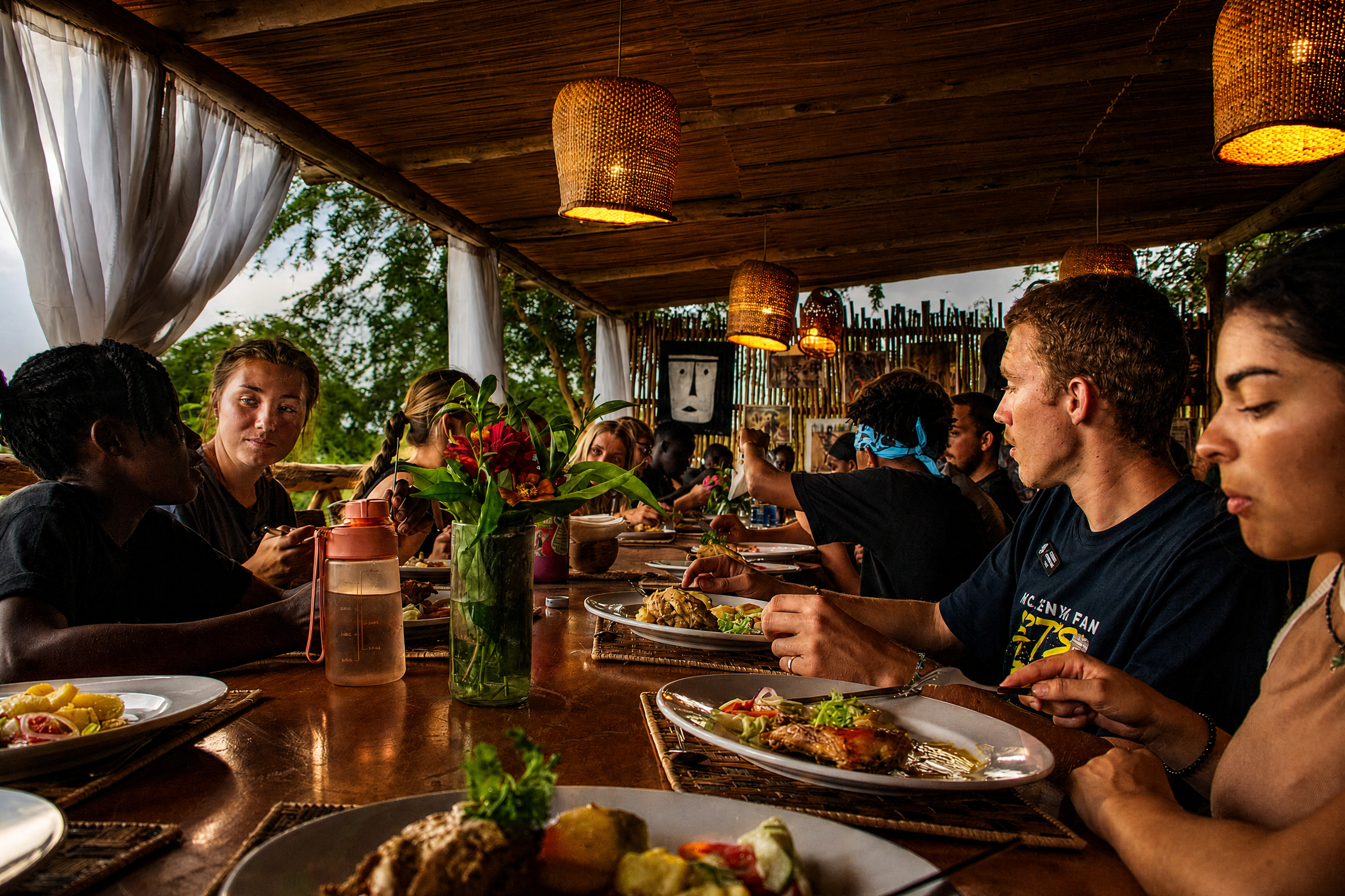 Guests dining at The Elephant Oasis terrace under woven pendant lights, Murchison Falls Uganda